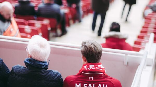 Fans in red jerseys sit in a stadium, showcasing football spirit with vibrant energy.