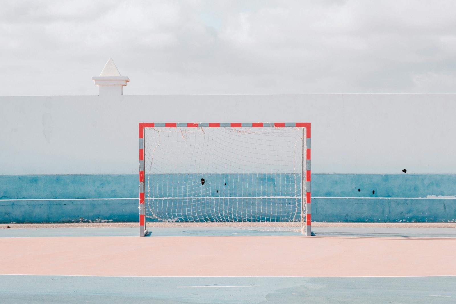 Bright sunny handball court with a vibrant goalpost. Perfect for sports or leisure themes.