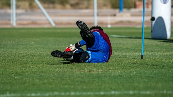 Soccer player dives during training, showcasing agility and skill on grass field.