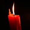 Close-up of a burning red candle glowing in the dark, symbolizing warmth and hope.