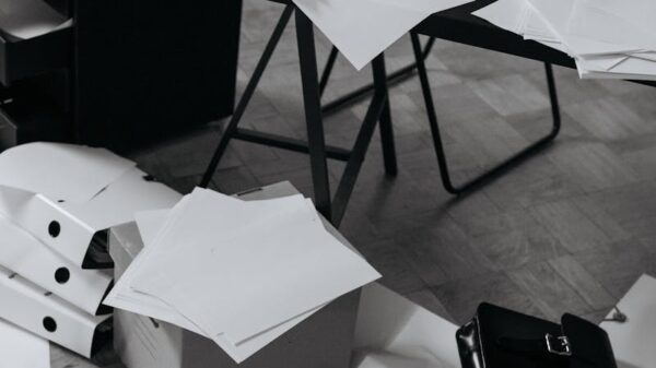 A chaotic office desk covered with scattered papers, folders, and a briefcase.