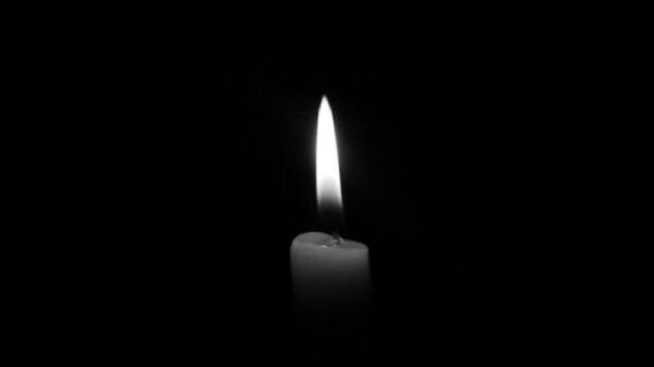 A solitary candle flame against a plain black backdrop, epitomizing simplicity and tranquility.