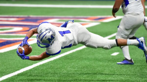 Football player making an incredible diving catch during a high-energy game in the stadium.