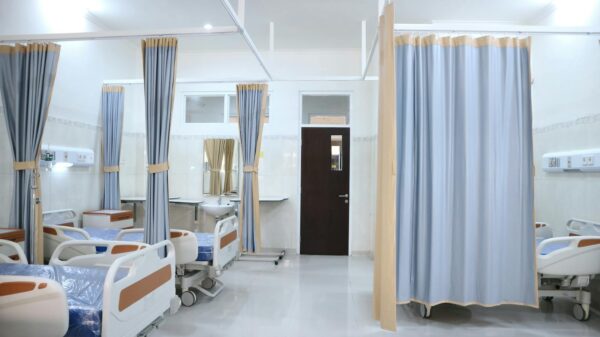 Spacious hospital ward in Surabaya, Indonesia with multiple medical beds and privacy curtains.