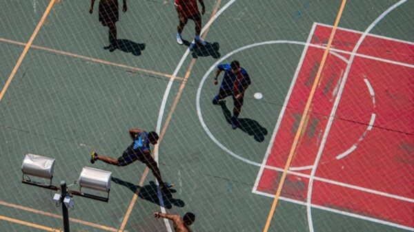 Dynamic aerial shot of a fast-paced sports game on an outdoor multi-use court, showcasing action and teamwork.