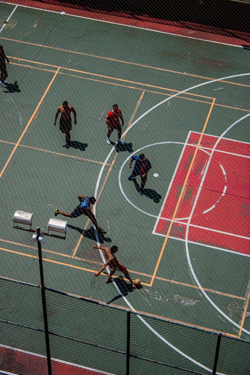 Dynamic aerial shot of a fast-paced sports game on an outdoor multi-use court, showcasing action and teamwork.