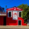 Colorful urban building in Chios with red facade and artistic mural under blue sky.