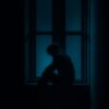 a man sitting on a window sill in the dark