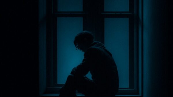 a man sitting on a window sill in the dark