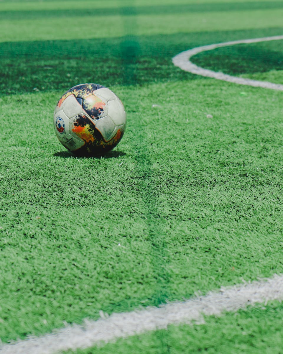 A soccer ball rests on a vibrant green field, ready for a match.