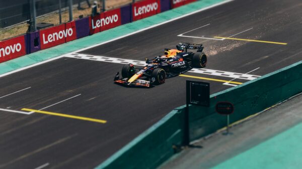 Formula 1 car speeding across the finish line on a racetrack, emitting sparks.