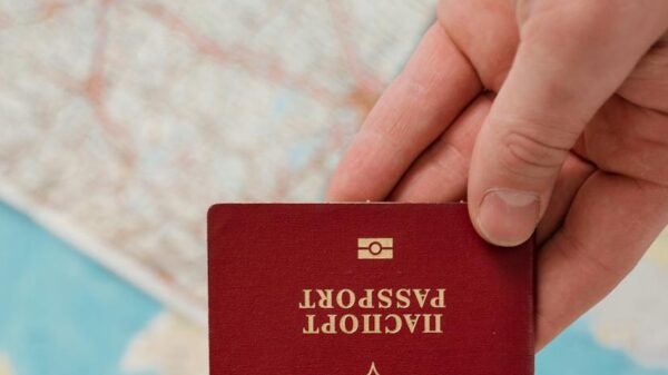 A hand holding a Russian passport over a map, suggesting travel preparation.