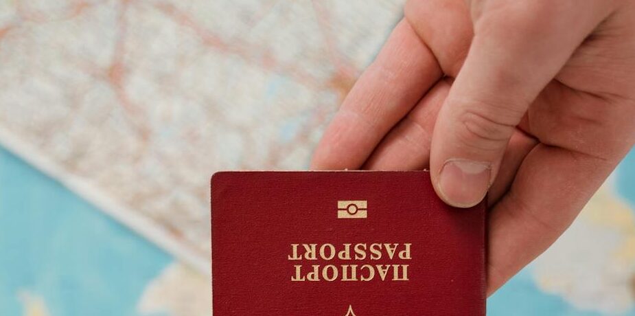 A hand holding a Russian passport over a map, suggesting travel preparation.