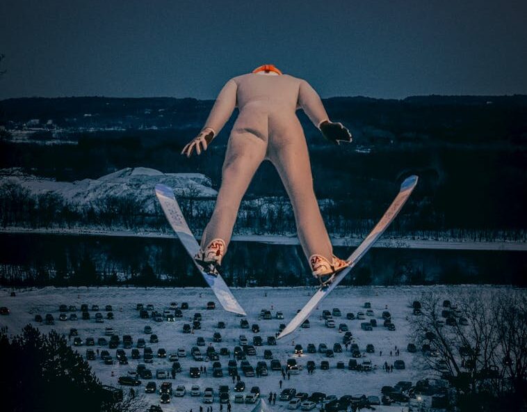 A thrilling shot of a ski jumper in mid-air against a snowy backdrop, showcasing winter sports excitement.