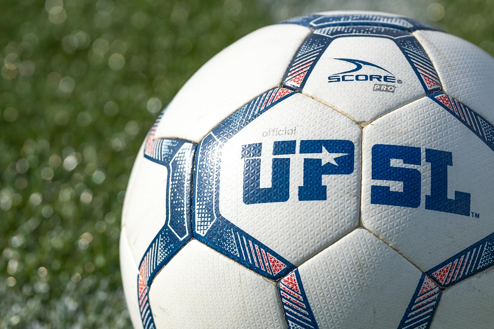 Detailed shot of a UPSL soccer ball on green grass, perfect for sports themes.