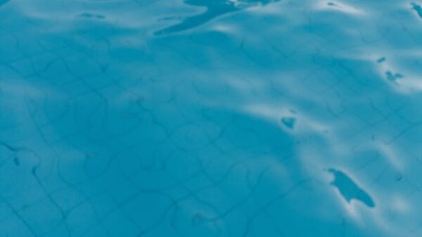 Close-up of a vibrant blue swimming pool surface with gentle ripples and tile lines visible underwater.