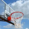 A basketball hoop and backboard set against a clear blue sky, capturing the essence of outdoor sports.