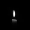 A solitary candle flame against a plain black backdrop, epitomizing simplicity and tranquility.