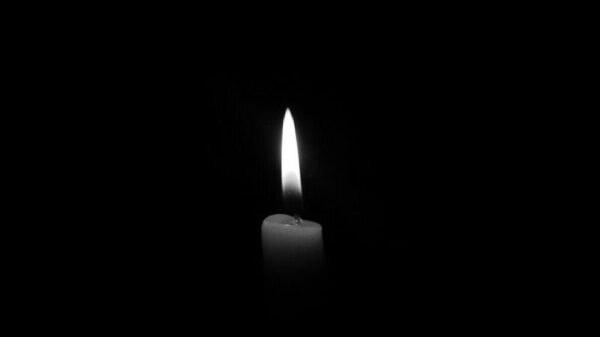 A solitary candle flame against a plain black backdrop, epitomizing simplicity and tranquility.