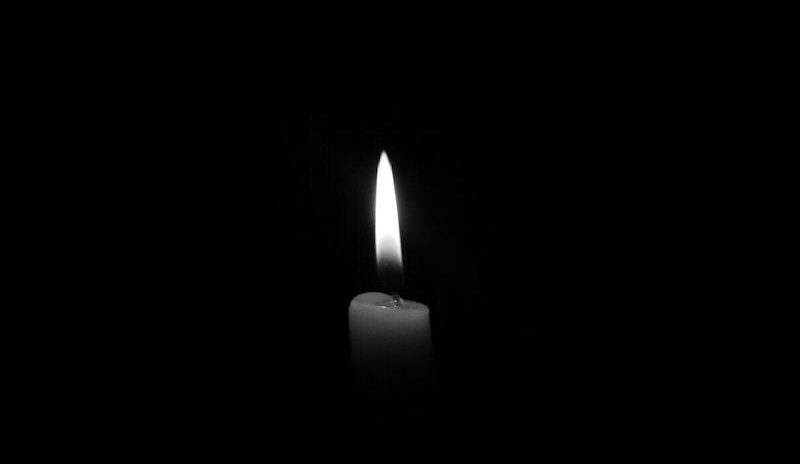 A solitary candle flame against a plain black backdrop, epitomizing simplicity and tranquility.