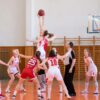 Exciting women's basketball game in a school gym, showcasing teamwork and athleticism.