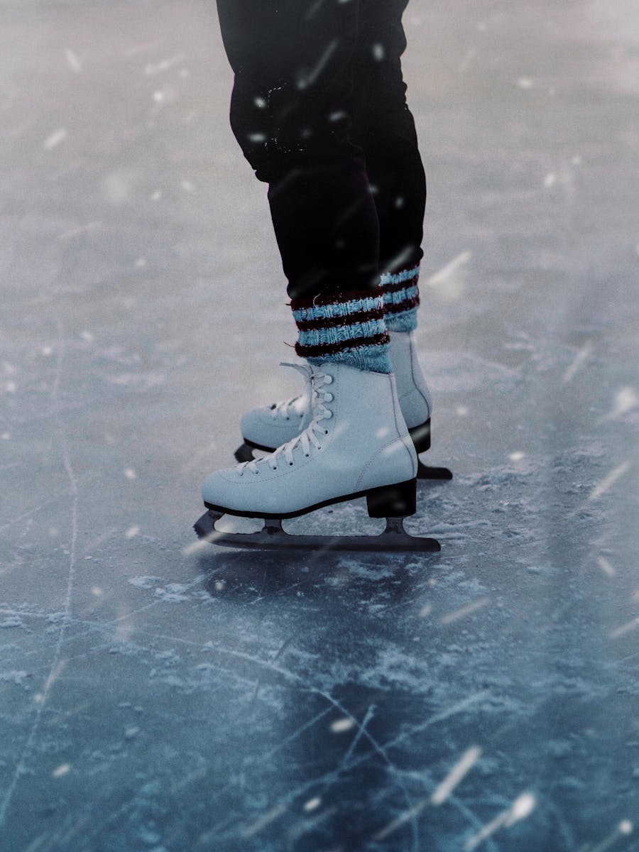 Close-up of person ice skating outdoors, showcasing ice skates in winter setting.