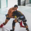 Two MMA fighters grapple intensely in a training gym, showcasing skill and strength.