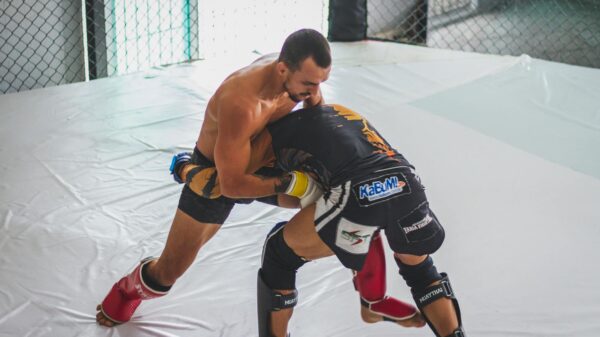 Two MMA fighters grapple intensely in a training gym, showcasing skill and strength.