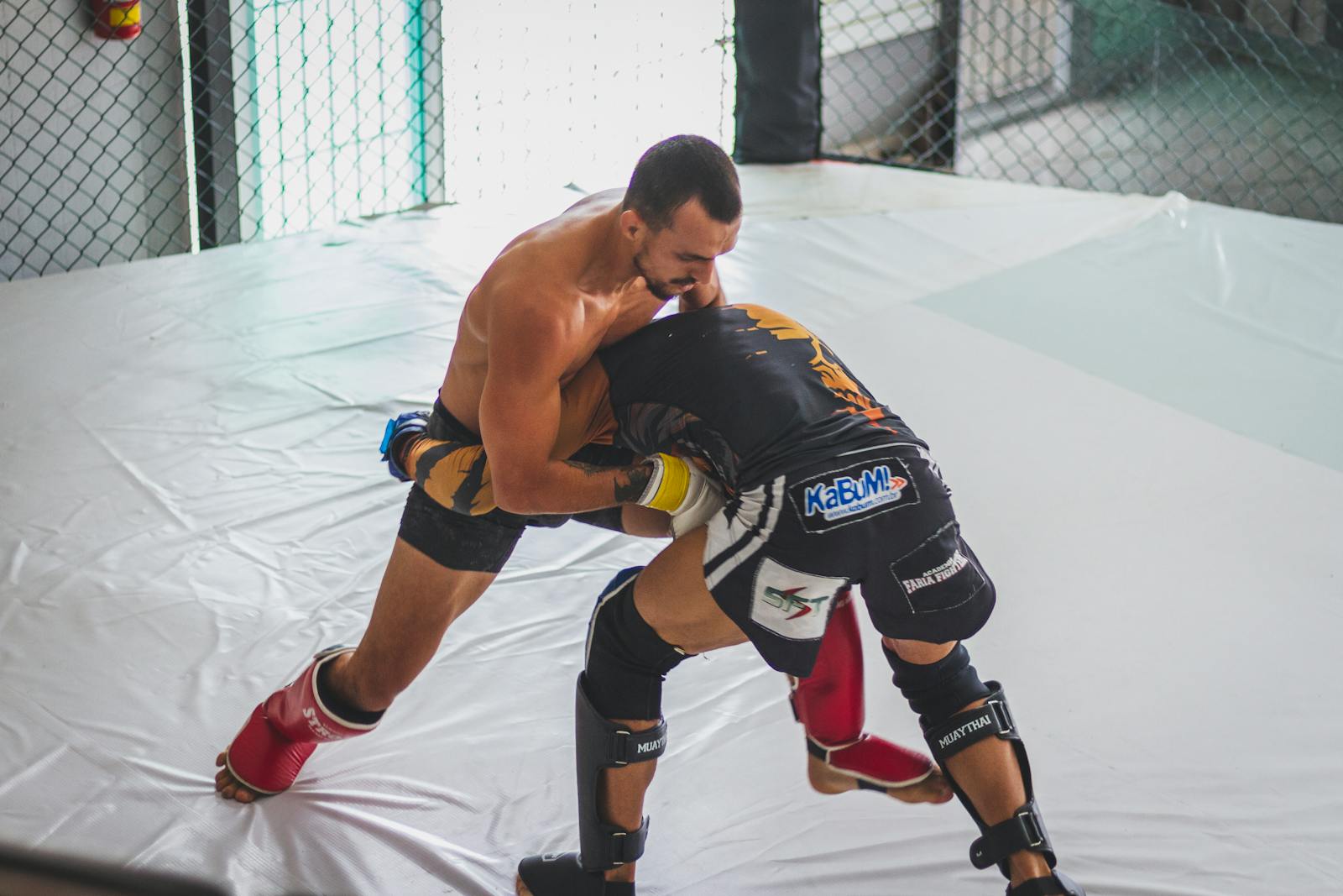 Two MMA fighters grapple intensely in a training gym, showcasing skill and strength.