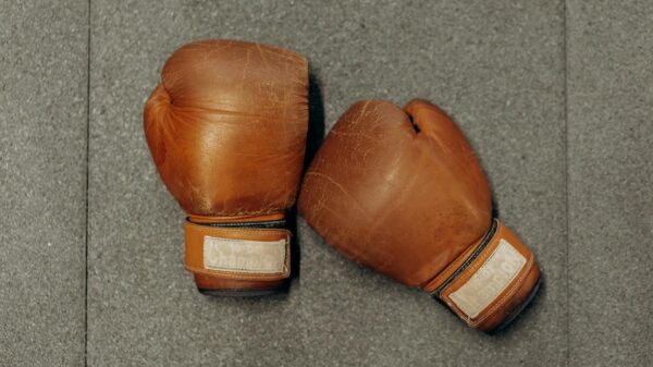 Brown leather boxing gloves on a textured gray gym surface.