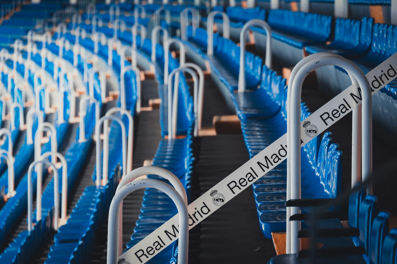 Rows of blue stadium seats in Madrid's iconic Bernabéu Stadium, featuring Real Madrid branding.