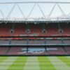 View of Arsenal's iconic Emirates Stadium with empty stands and lush football pitch.