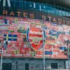 Vibrant wall art at Emirates Stadium featuring Arsenal flags and crest in London, UK.
