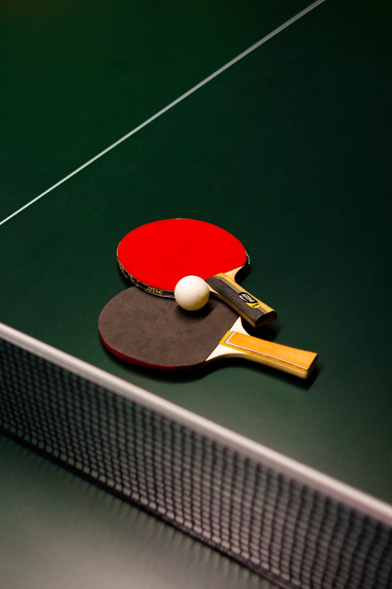 Table tennis paddles and ball on a green table. Ideal for sports themes.