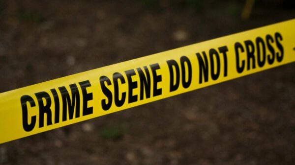 Close-up of crime scene tape with 'Do Not Cross' text, outdoors setting.