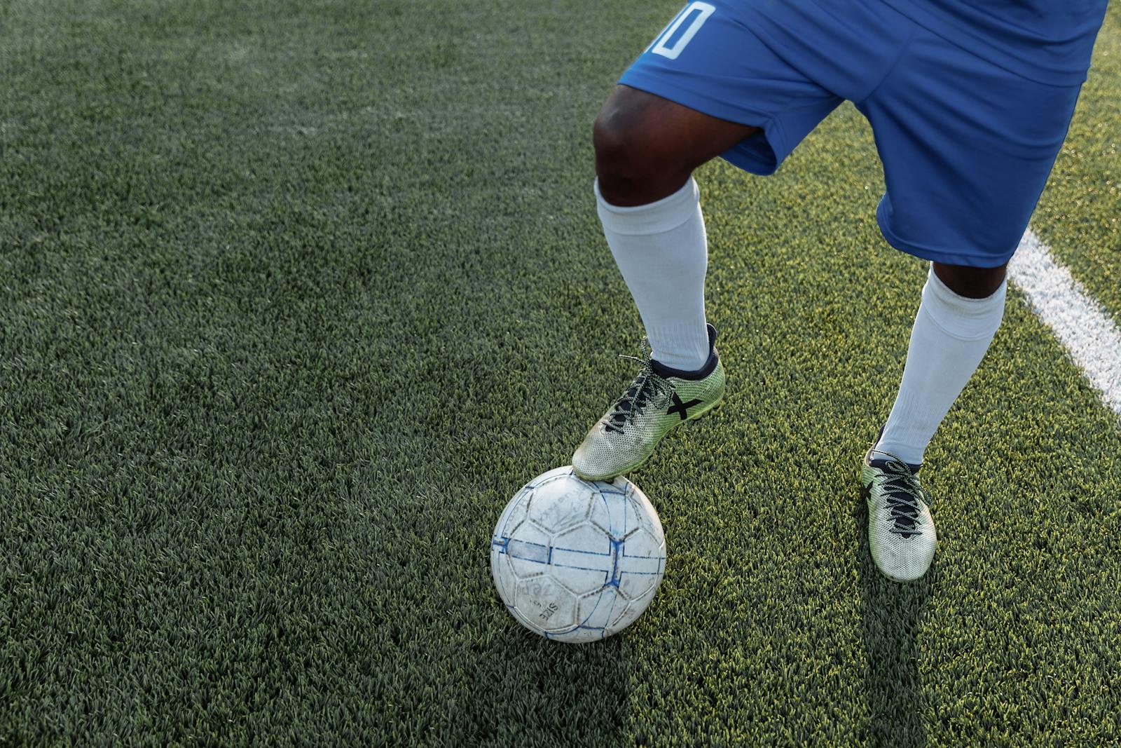 Close-up of a player controlling a soccer ball on a grass field.