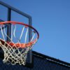 A vibrant outdoor basketball hoop with net set against a clear blue sky, ideal for sports visuals.