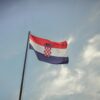 The Croatian flag blowing in the wind against a clear blue sky, symbolizing national pride.