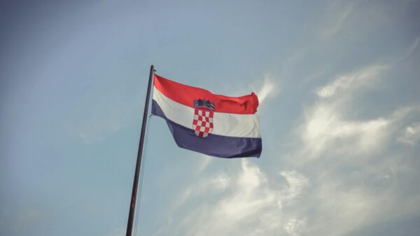 The Croatian flag blowing in the wind against a clear blue sky, symbolizing national pride.