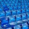 Vibrant blue plastic seats in a stadium forming a pattern, offering ample copy space.