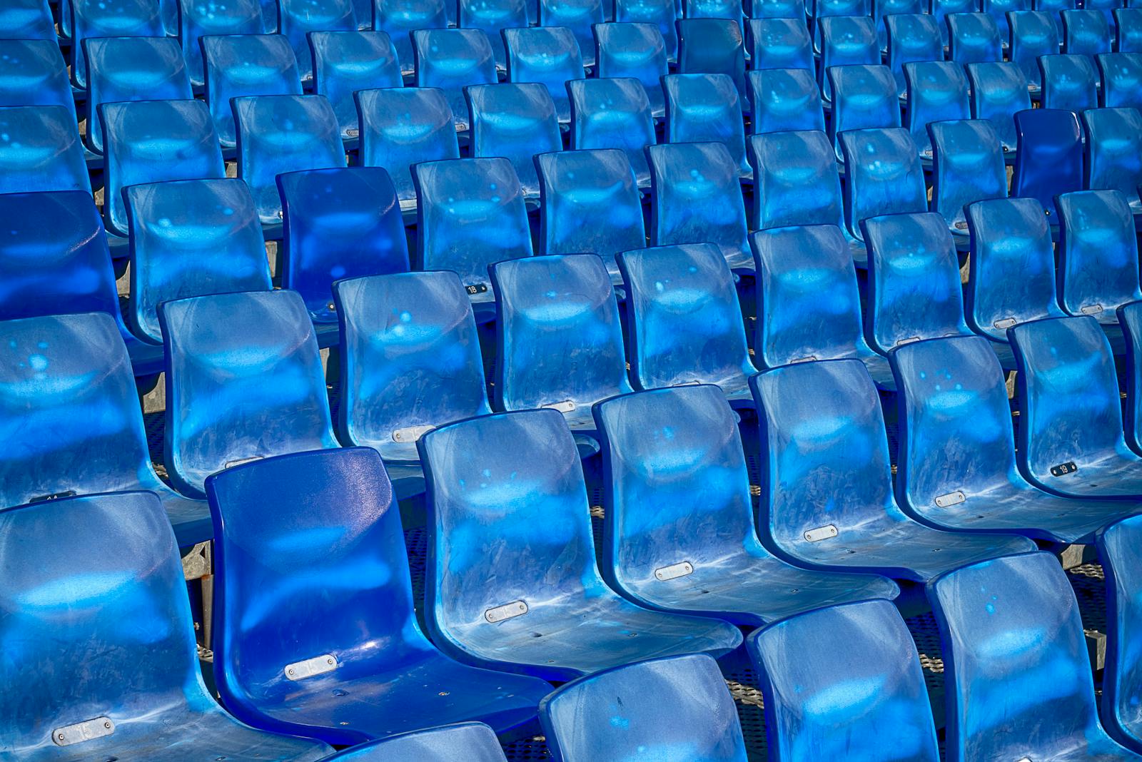 Vibrant blue plastic seats in a stadium forming a pattern, offering ample copy space.