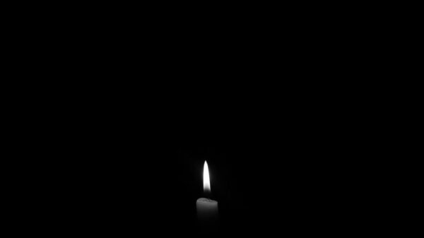 A solitary candle flame against a plain black backdrop, epitomizing simplicity and tranquility.