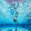 Dynamic underwater view of a swimmer practicing freestyle in a clear pool.