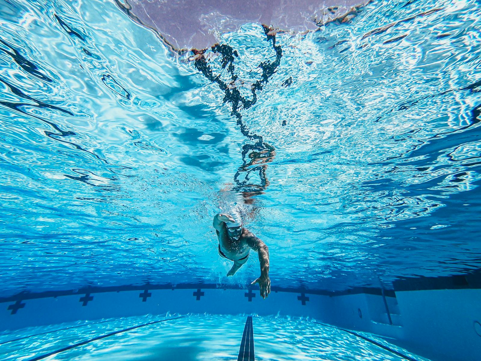 Dynamic underwater view of a swimmer practicing freestyle in a clear pool.