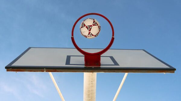 A soccer ball perfectly positioned in a basketball hoop against a clear sky, symbolizing achievement.
