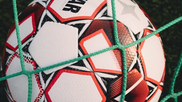 Close-up of a soccer ball trapped in a net on a grassy pitch, perfect for sports themes.