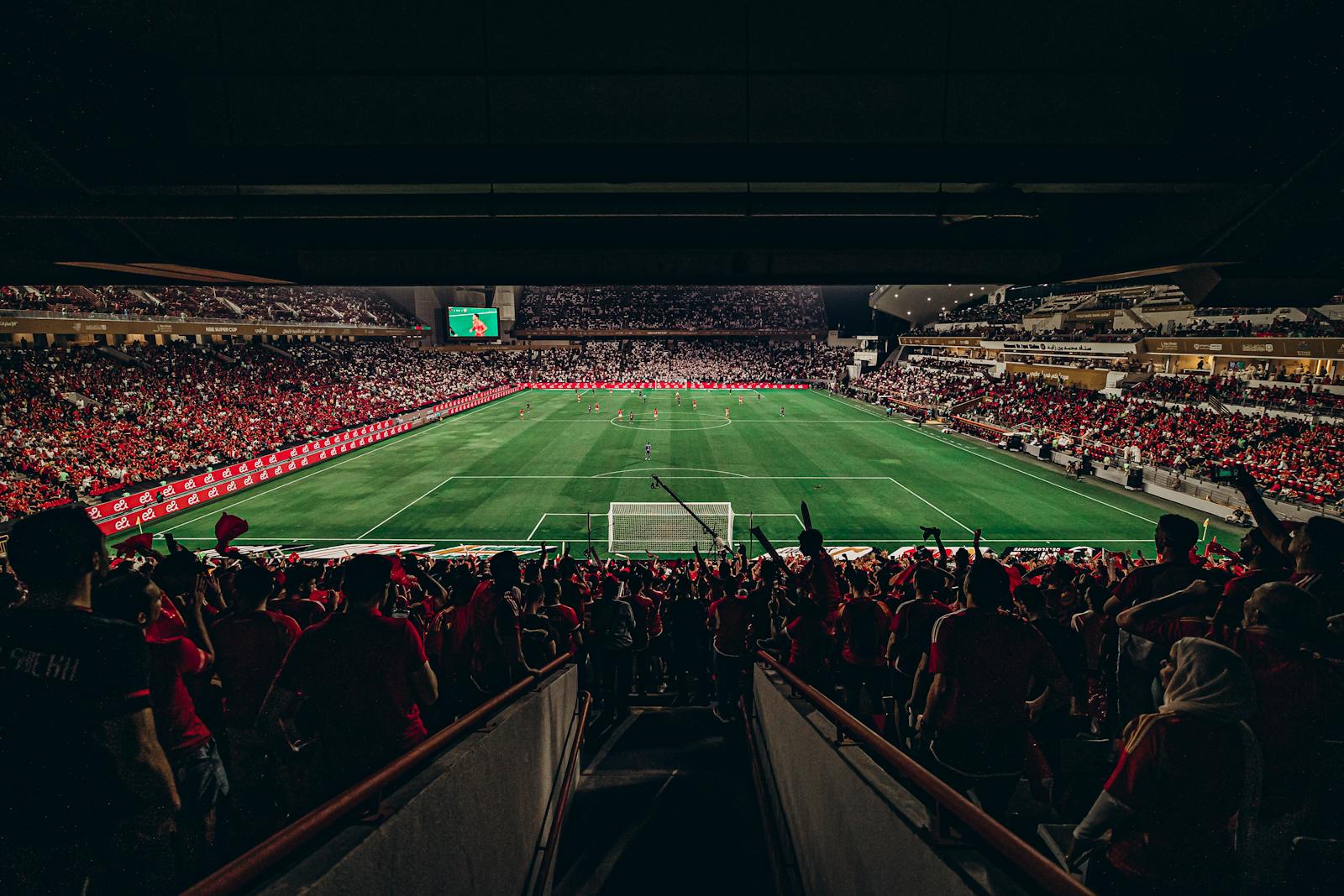 An exciting football match with passionate fans filling the stadium under bright lights, capturing sports energy.