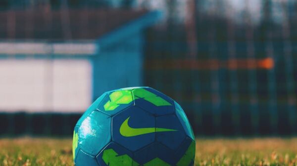 Close-up of a blue and green soccer ball on a grass field, perfect for sports themes.