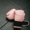 Overhead shot of pink boxing gloves on black gym mat. Ideal for fitness and sports concepts.