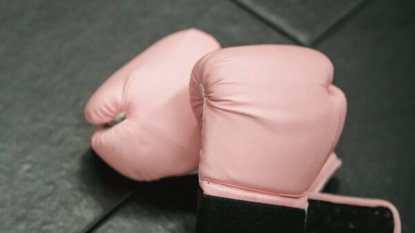 Overhead shot of pink boxing gloves on black gym mat. Ideal for fitness and sports concepts.